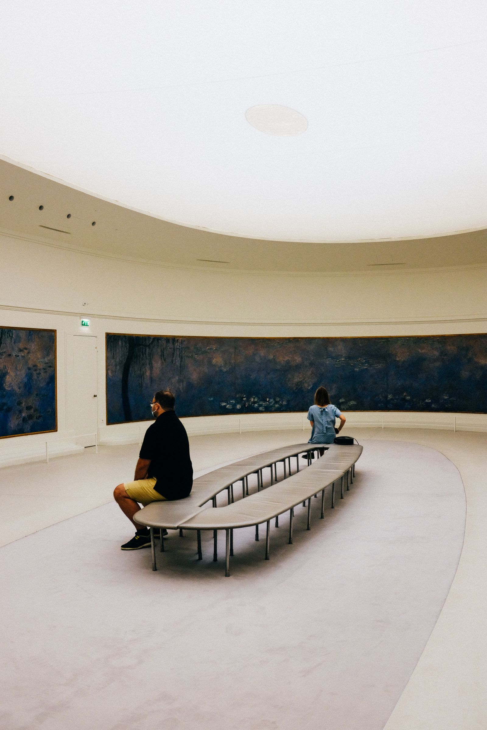A quiet gallery with framed paintings and a bench