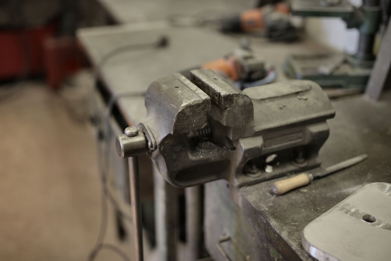 A workbench scattered with hand tools and metal parts